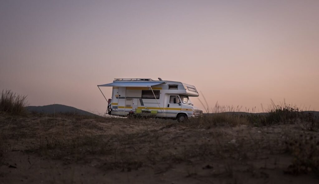 A serene view of an RV parked amidst nature during sunset, capturing a travel adventure.